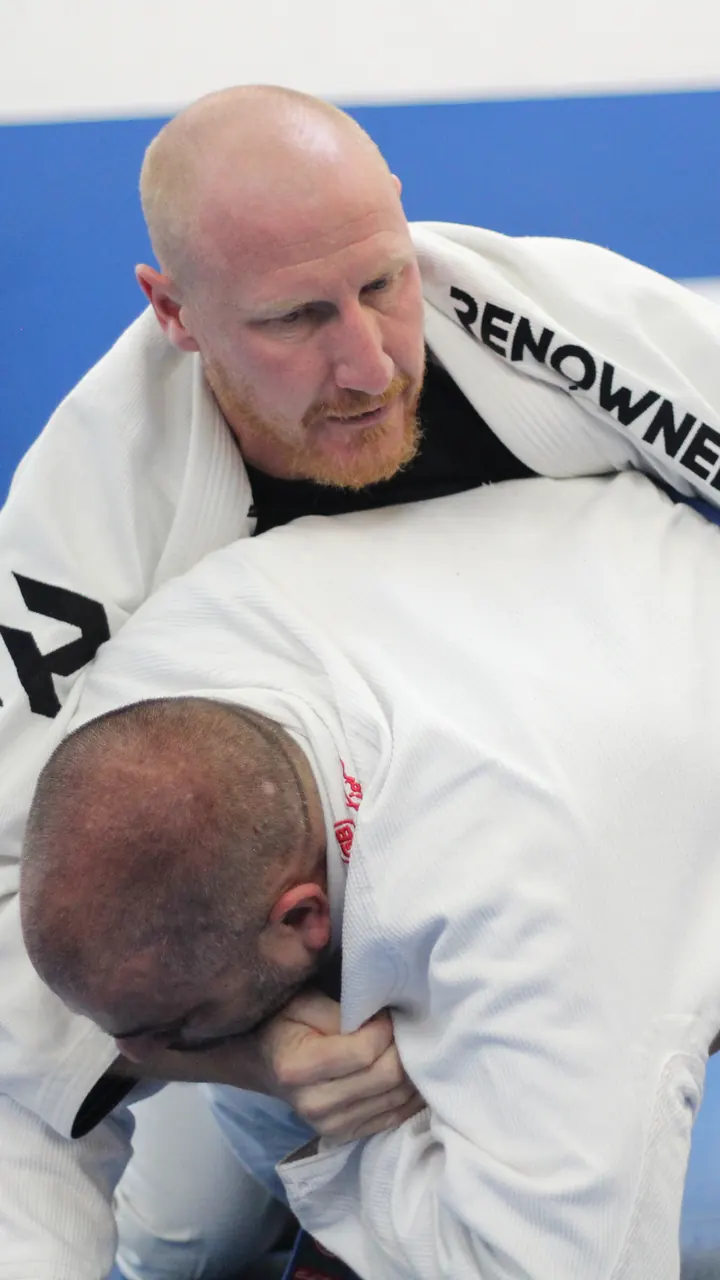 A coach demonstrating a grip to a student during a class