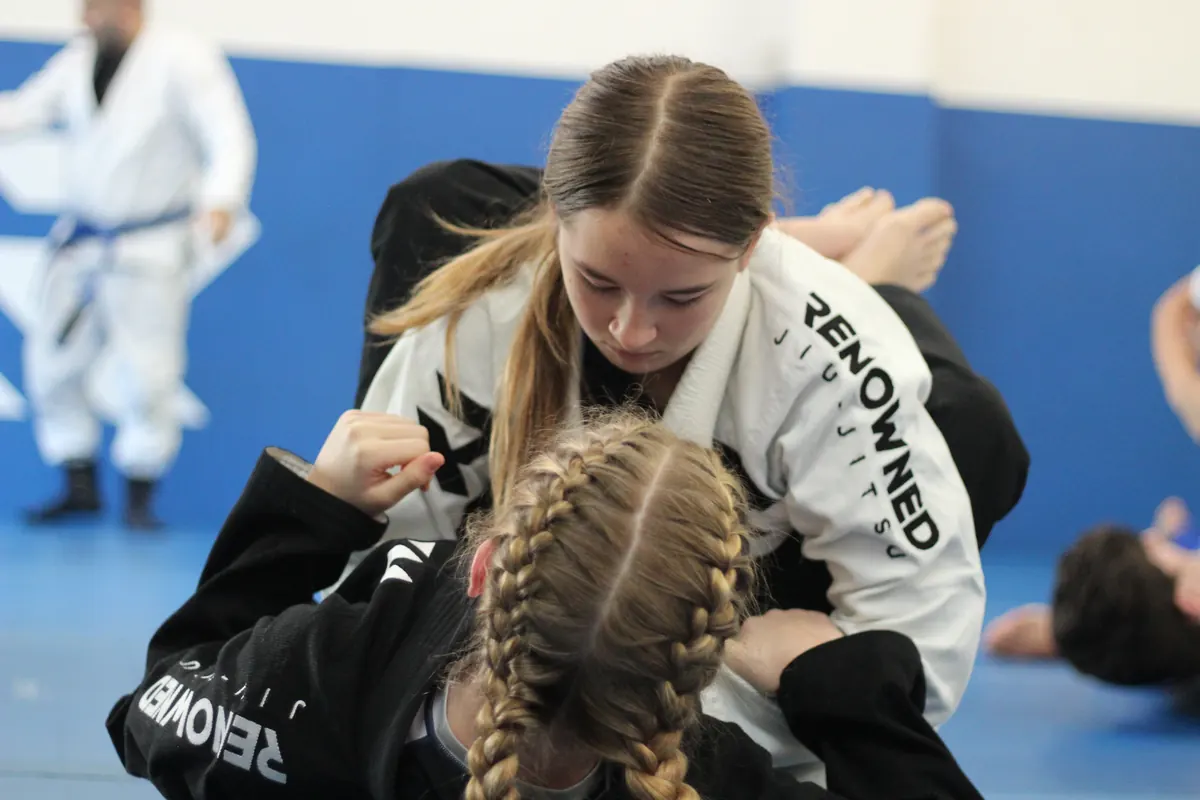 A teenager in a black gi taking grips against a training partner