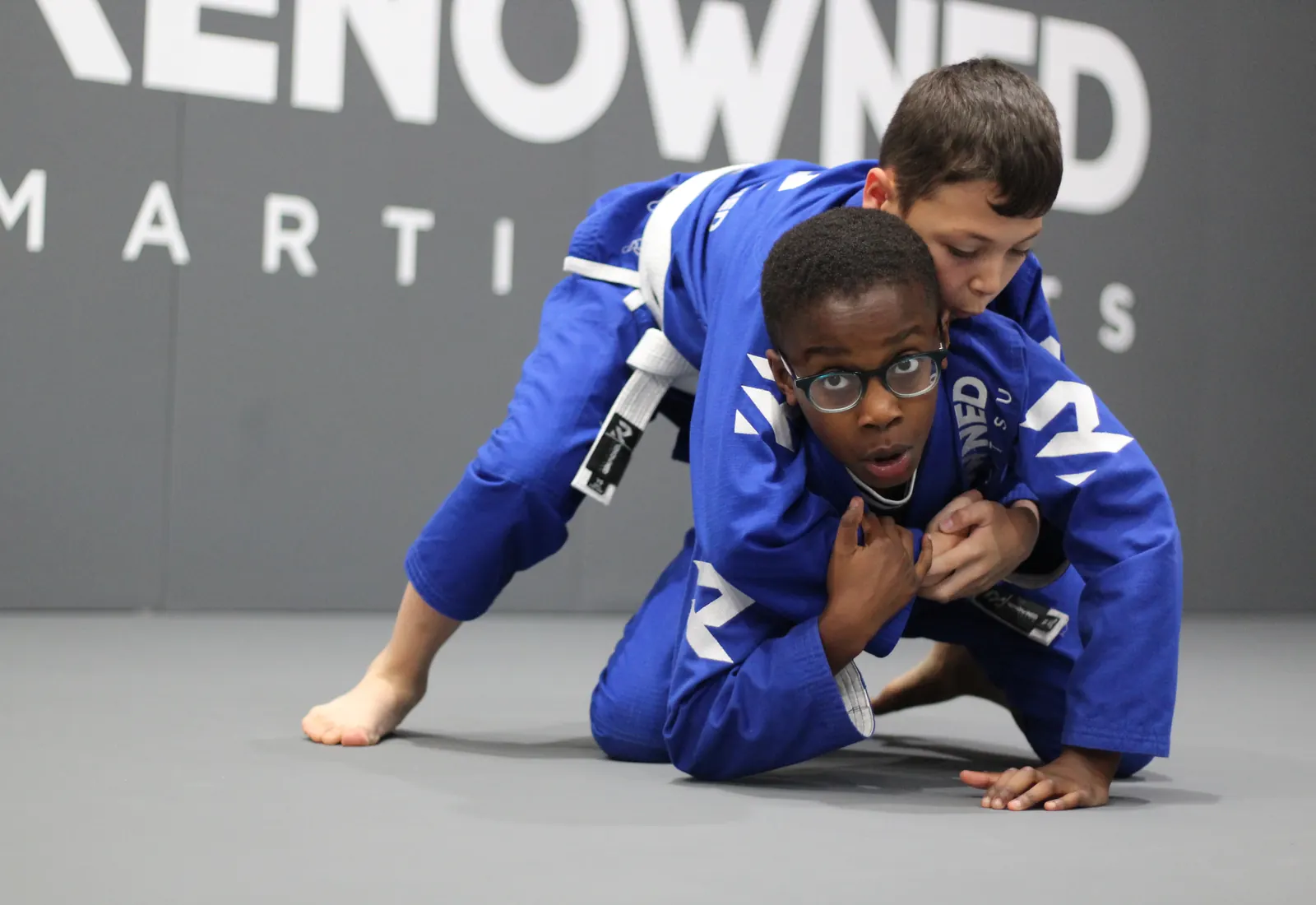A child mid drill in a kids jiu jitsu class, concentrating hard