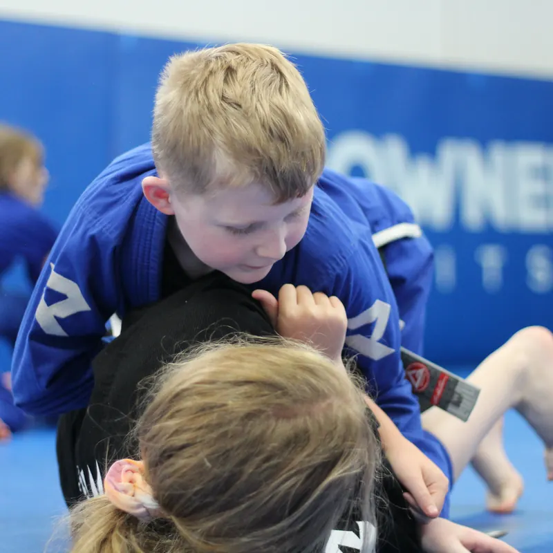 Two children aged seven to eleven gripping each other's gis