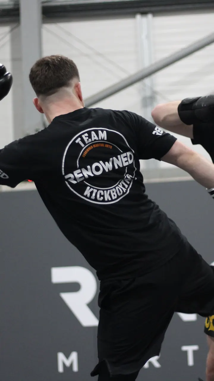 A student throwing a knee on the pads in a kickboxing class