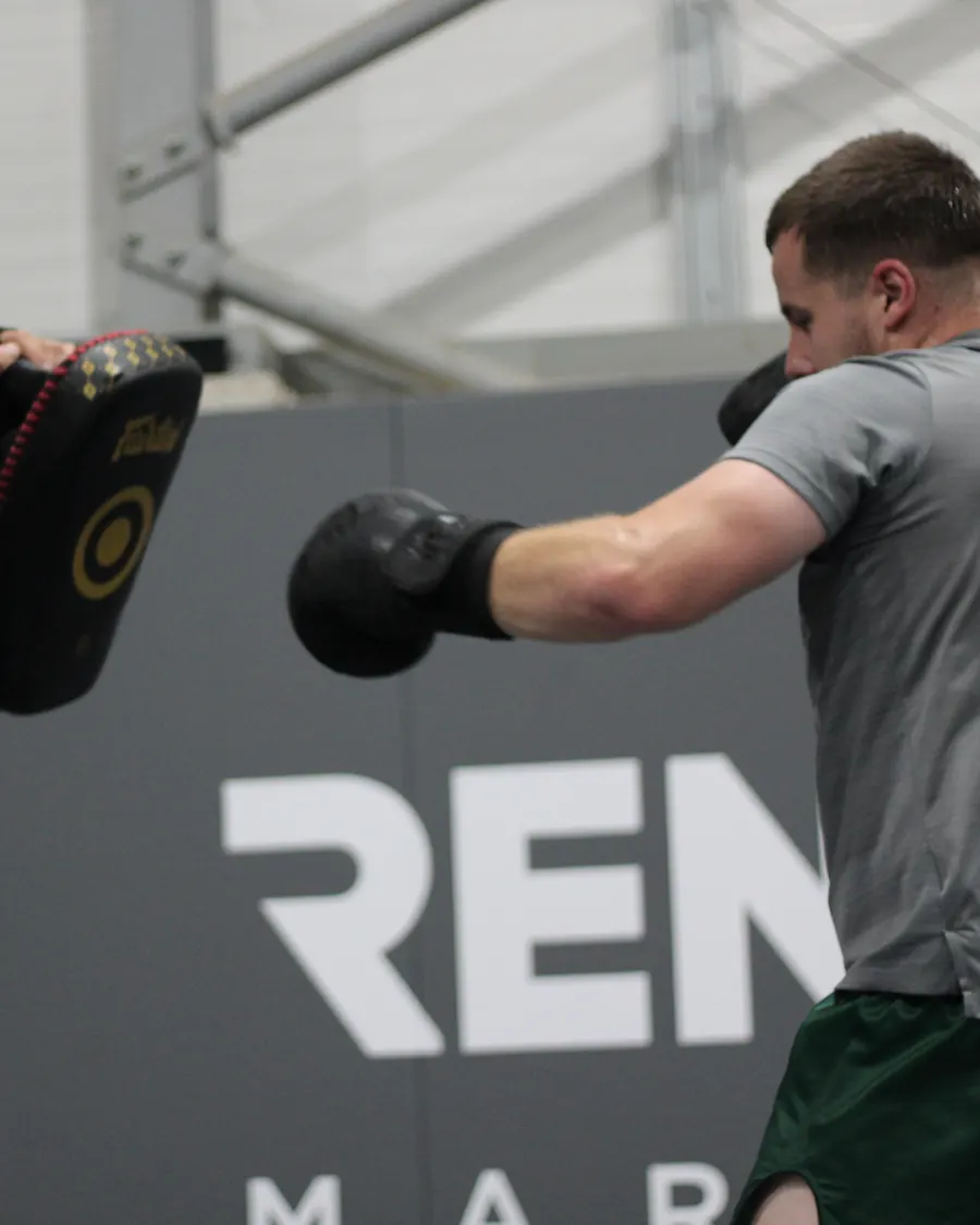 A student throwing a punch onto the coach's pads
