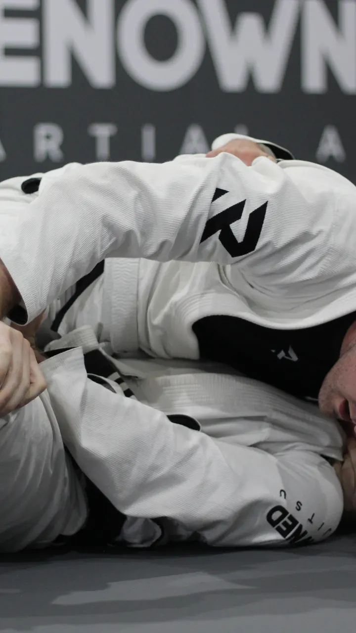 An adult jiu jitsu class working through a position